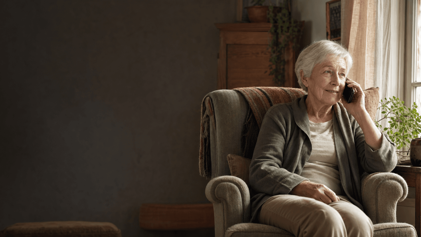 An older adult enjoying a warm phone conversation in a quiet living room.